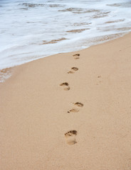 Fototapeta na wymiar Footsteps on the sand beach