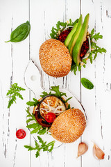 Fresh homemade two veggies burgers over white rustic table. Vegan grilled eggplant, arugula, sprouts and pesto sauce burger. Veggie beet and quinoa burger. Top view, overhead, flat lay