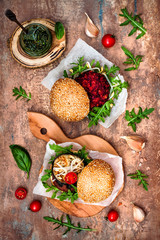 Fototapeta na wymiar Two veggies burgers over stone vintage background. Vegan grilled eggplant, arugula, sprouts and pesto sauce burger. Veggie beet and quinoa burger. Top view, overhead, flat lay. Copy space