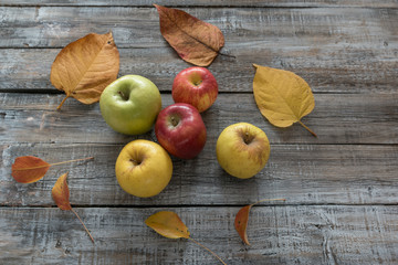 Apples and leaves on wooden boards background. Autumn concept
