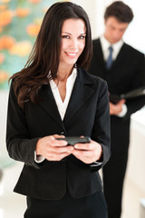 Businesswoman texting with mobile phone in hotel office lobby