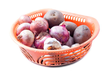 Onions, garlic and potato on orange basket