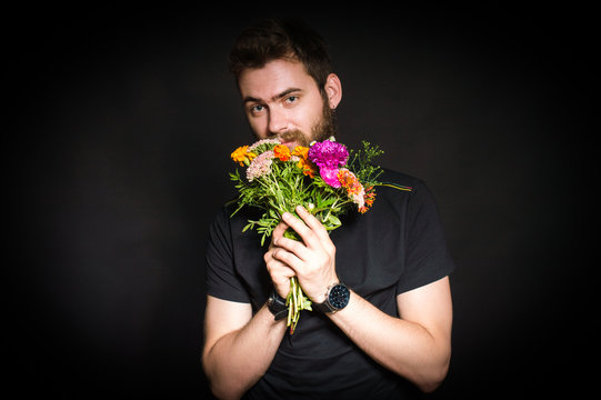 Bearded Man Holding A Bouquet Of Flowers. On A Black Background.