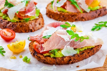 bruschetta with prosciutto, avocado, tomatoes, arugula and cheese