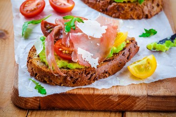 bruschetta with prosciutto, avocado, tomatoes, arugula and cheese