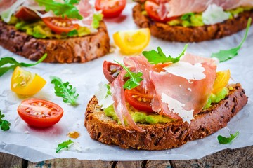 bruschetta with prosciutto, avocado, tomatoes, arugula and cheese