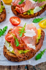 bruschetta with prosciutto, avocado, tomatoes, arugula and cheese