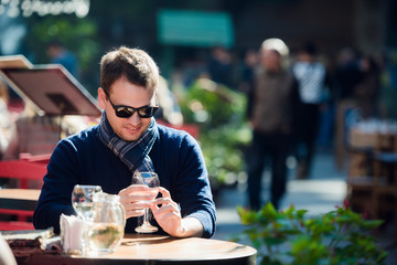 Man checking his cellphone while sitting at outdoors street cafe