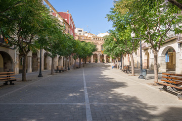 Fototapeta na wymiar The Plaça de la Quatera in the village Falset, the small capital of the region of Priorat. It is a square with trees and arcades, where the former Renaissance palace of the Count now the Town Hall is