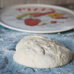 Ball of pizza dough on a rustic wooden background with dusting of flour