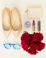 Obraz na płótnie Canvas Nude colored high heels still life with wallet, roses, sun glasses and red lipstick, top view