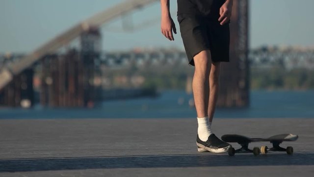 Young man with a skateboard. Legs moving in slow-mo. Sport for risky people. Vibe of the youth.