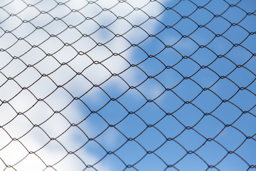 Fototapeta premium Metal mesh netting on the blue sky background and clouds