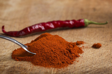 Spoon filled with red hot paprika powder and one dried chilli
