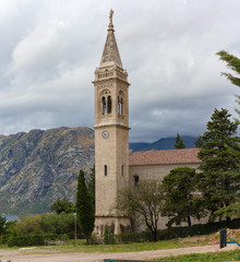 Fototapeta na wymiar The bell tower on a background of mountains in cloudy weather in