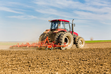 Obraz premium Farmer in tractor preparing land with seedbed cultivator
