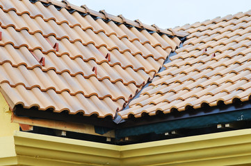 Obraz na płótnie Canvas Roof house with tiled roof on blue sky. detail of the tiles and corner mounting on a roof, horizontal. roof protection from snow board (Snow guard) on house construction. unfinished roof