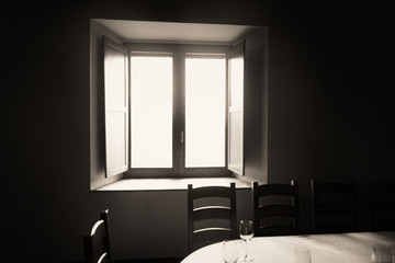 A flood of light coming into a room from a wooden window. A table and some dishes. Retro sepia colors.
