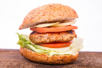 Hamburger with fried onion, tomatoes, iceberg lettuce on a wooden board