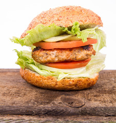 Hamburger with fried onion, tomatoes, iceberg lettuce on a wooden board