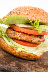 Hamburger with fried onion, tomatoes, iceberg lettuce on a wooden board