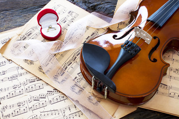 Marriage proposal with gold ring and violin on music notes