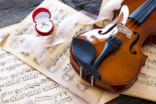 Marriage proposal with gold ring and violin on music notes