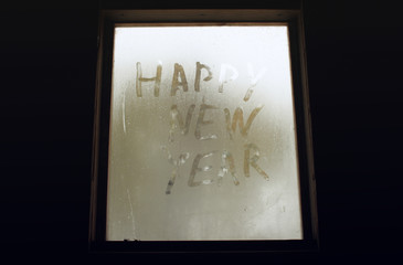 The inscription "happy new year" on the misted window