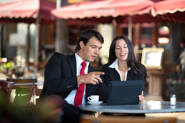 Businessman and Businesswoman Discussing Digital Tablet at Sidew