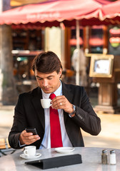 Businessman Texting with Espresso at Sidewalk Cafe