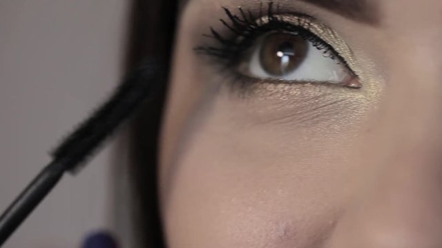 makeup girl paints eyelashes, brown eyes