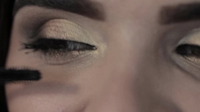 makeup girl paints eyelashes, brown eyes