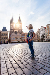 Fototapeta premium Beautiful young woman points to the Church of Virgin Mary in Old Town Square in Prague. Kostel Panny Marie pred Tynem.