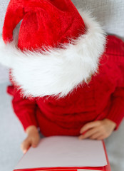 Little girl in red hat writing a letter to Santa Claus. Top view.