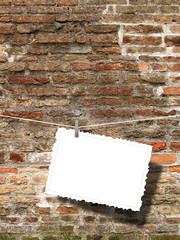 One blank postcard frame hanged by pegs against dirty brown brick wall background © ma3d.it