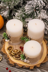 Obraz na płótnie Canvas Fir branch in snow, candles by cutting the tree, berries, dry citrus on wooden background