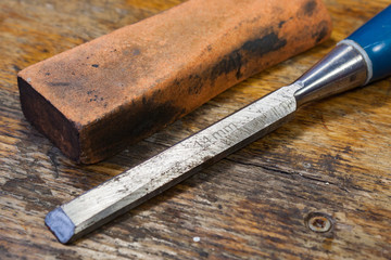 Old chisel and stone for sharpening on a table in a workshop