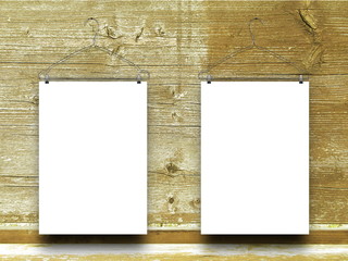 Two blank frames hanged by clothes hangers against yellow wooden boards background