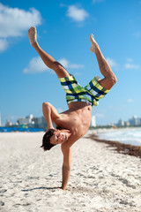 Young man on spring break clowning around doing handstand on South Miami Beach Florida