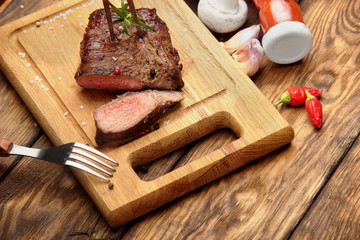 Overhead view of a portion of juicy grilled beef steak with on a textured wooden surface