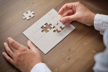 Image of businesswoman connecting elements of white puzzle