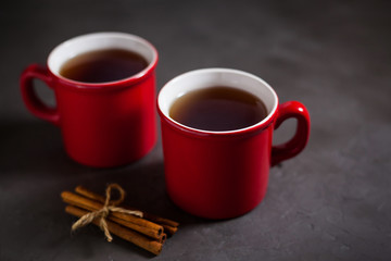 Red cups with tea on gray concrete background, cinnamon