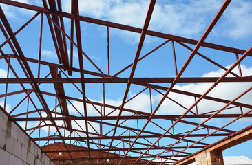 Roofing Construction. New Steel roof trusses details with clouds sky background. Industrial roofing.