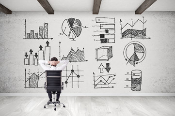 Man on chair looking at graphs