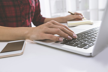 Woman in red checkered shirt is typing with one hand