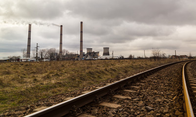 Fototapeta na wymiar Industrial scenery with a coal power plant smoke stacks and old railroad, on a gloomy autumn day