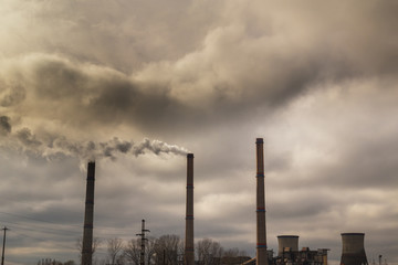 Air pollution from coal-powered plant smoke stacks, and industrial cityscape, on a gloomy, overcast day