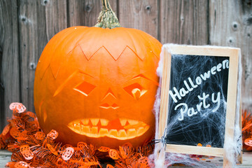 Tafel mit Text Halloween Party mit schaurigem Kürbis Spinnweben vor Holzhintergrund