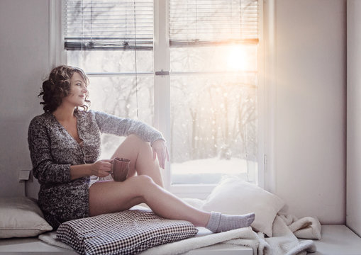 woman sitting beside window in the winter morning sun relaxing