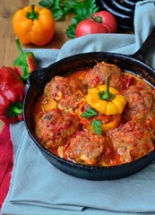 Stuffed bell pepper with minced meat and rice, and meatballs in tomato sauce in a frying pan